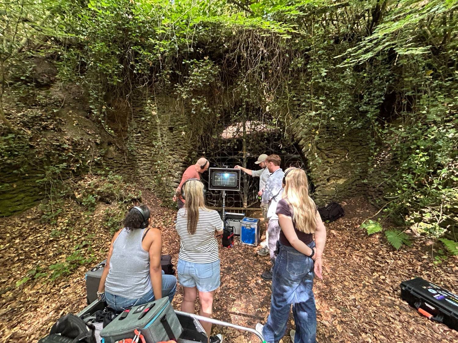 Location hire for TV and film production: a crew at work in front of the ivy-hung cave entrance