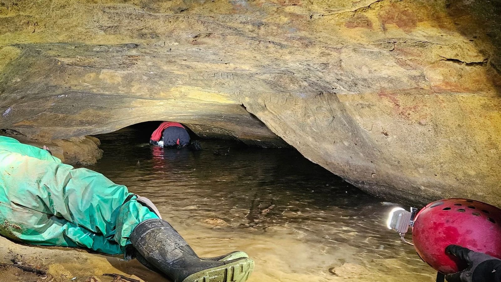 A caver crawling through the low water passage