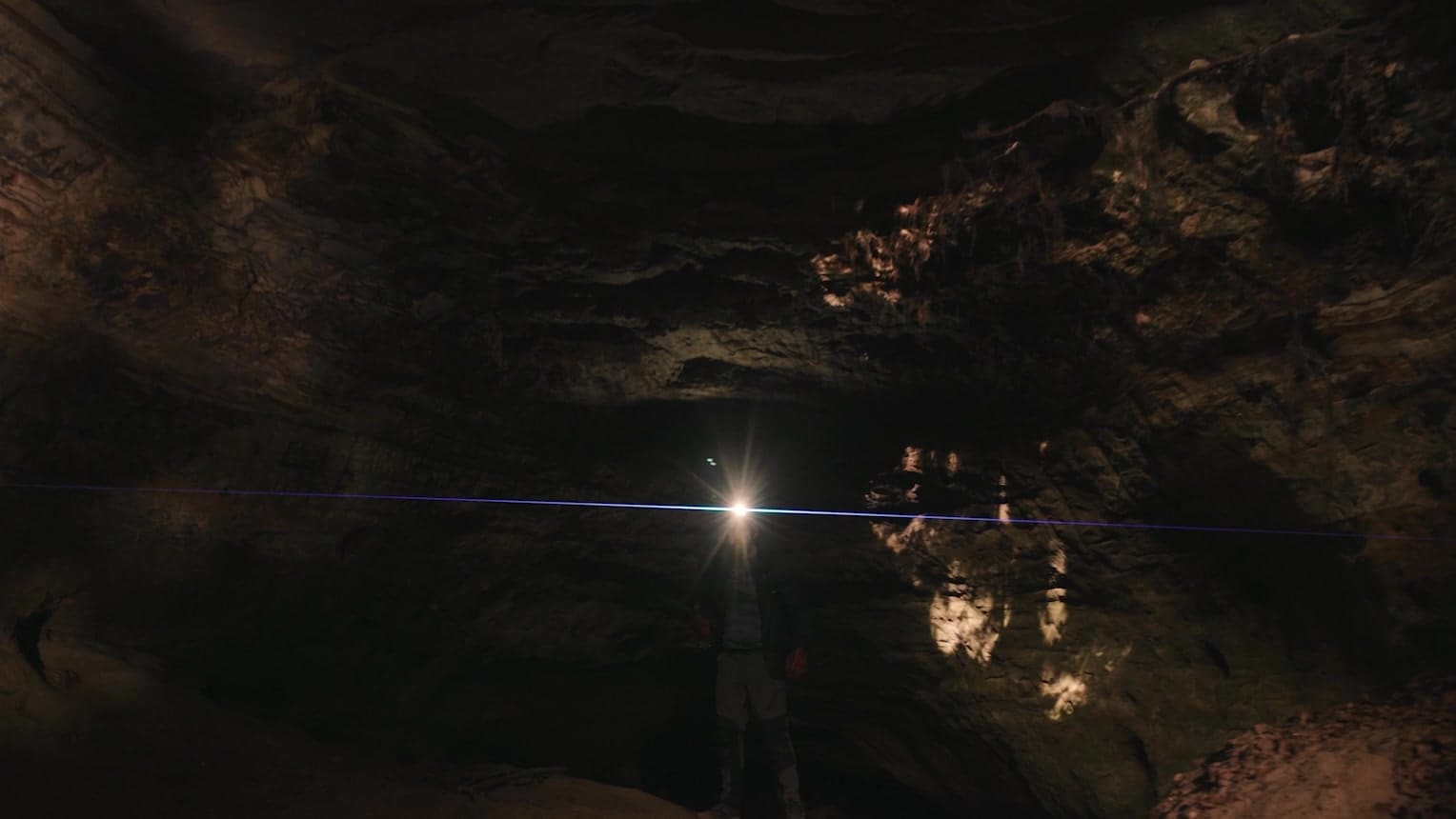 A headtorch lighting the sandstone walls of Mother Ludlam's Cave in the trailer