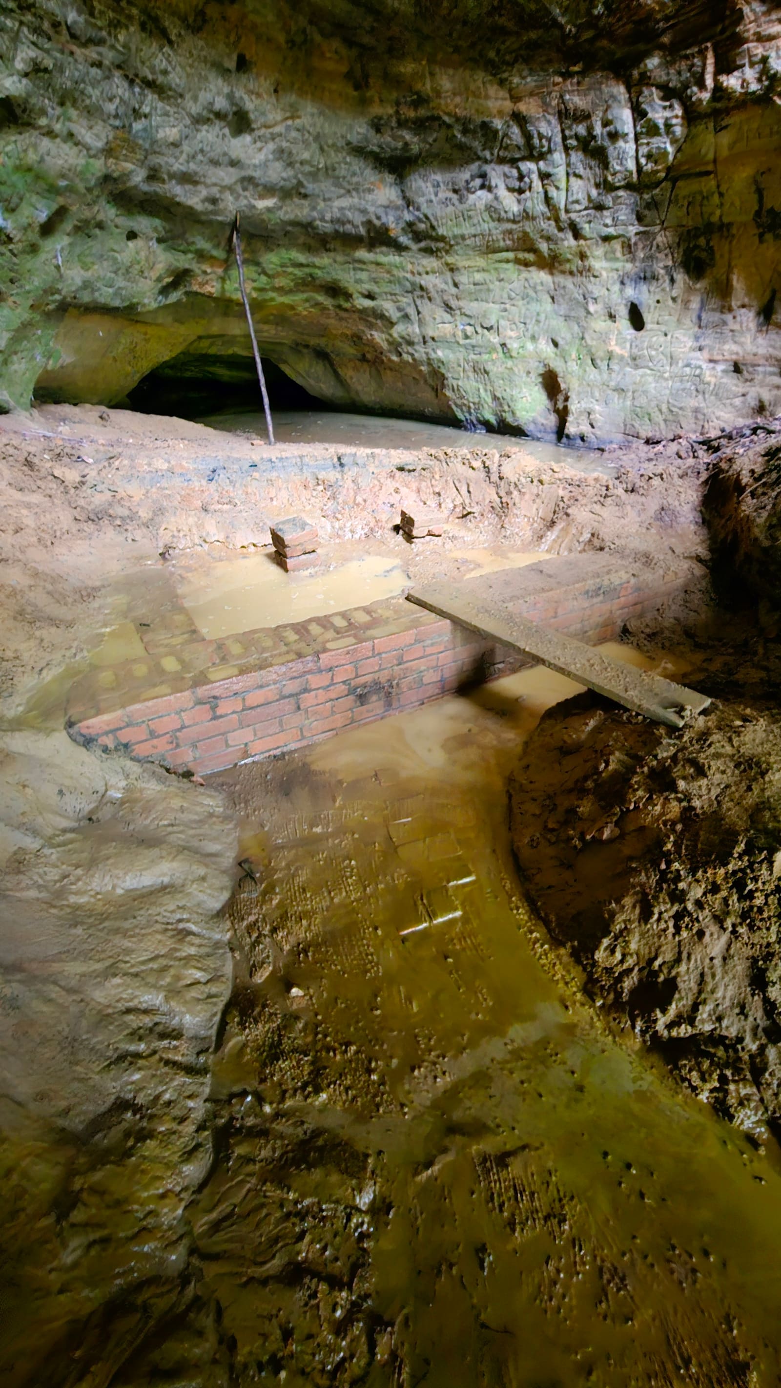 Inside the cave today, brick structure and pooling spring water